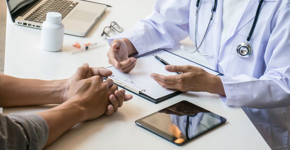 Doctor-consulting-with-patient-at-desk-in-medical-office Doctor-consulting-with-patient-at-desk-in-medical-office
