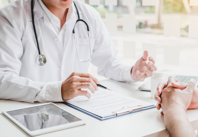 Doctor-consulting-with-patient-in-medical-office Doctor-consulting-with-patient-in-medical-office