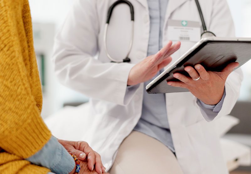 Doctor-reviewing-patient-information-on-tablet Doctor-reviewing-patient-information-on-tablet