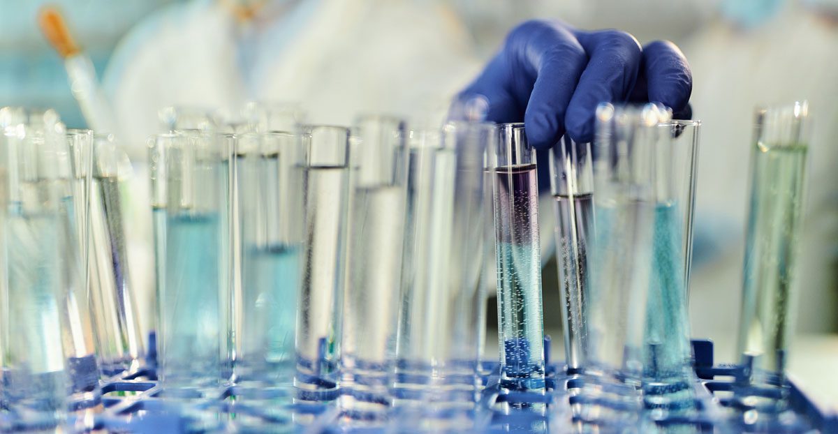 Scientist-handling-test-tubes-in-laboratory-research-facility Scientist-handling-test-tubes-in-laboratory-research-facility